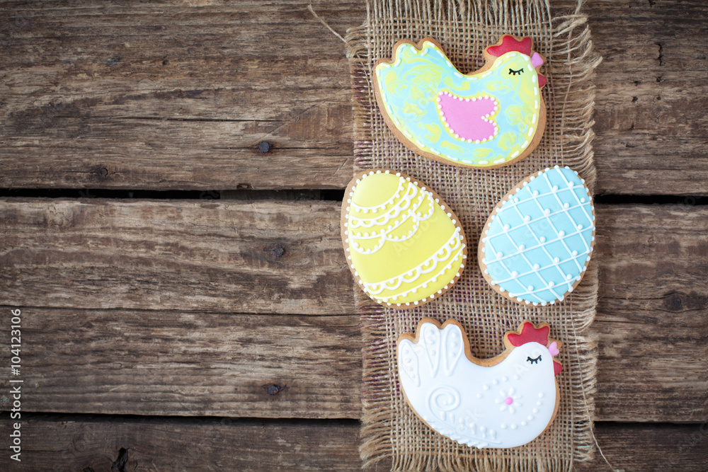 Homemade gingerbread cookies in the shape of the Easter chicken and painted eggs on a wooden table. Space for text and selective focus. Homemade gingerbread cookies in the shape of the Easter chicken and painted eggs on a wooden table. Space for text and selective focus.
