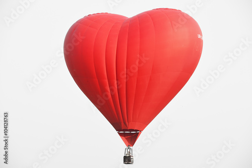 Red balloon in the shape of a heart against the blue sky.