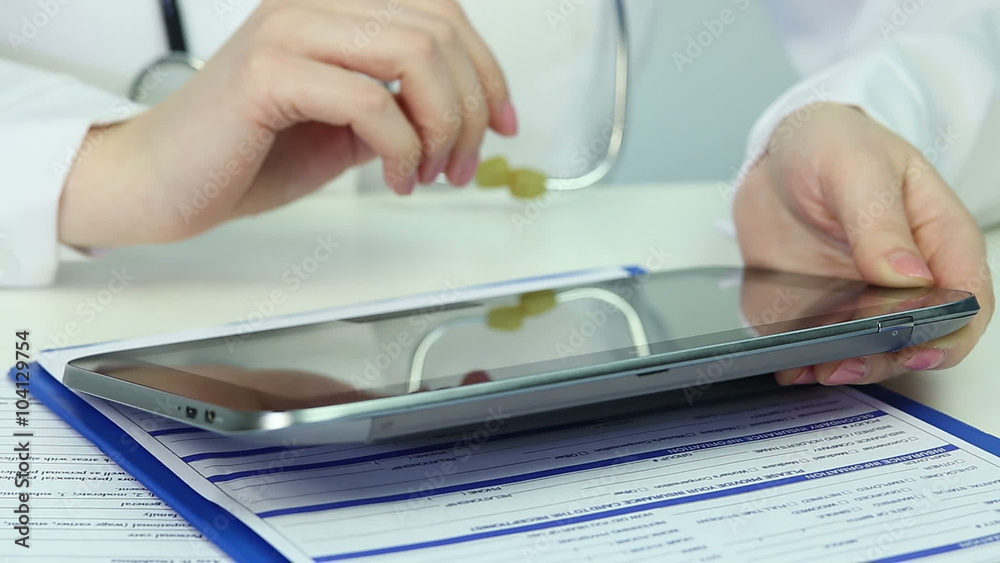 Physician browsing pages on tablet, consulting patients online, keeping records