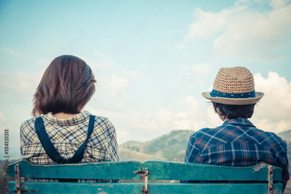 Back side of lovely couple sit on wooden chair with sky view