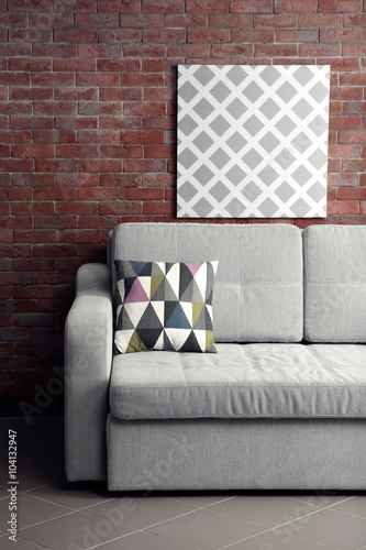 Grey sofa against brick wall in the room © Africa Studio