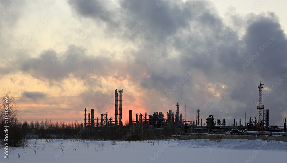 Refinery at sunset sky background. Frosty snowy winter evening. Refinery at sunset sky background. Frosty snowy winter evening.