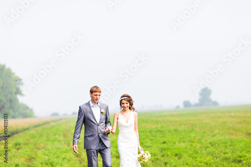 Young wedding couple walking on field  © satura_
