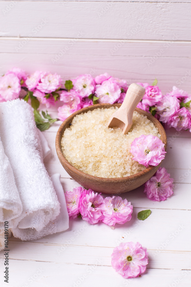 Organic sea salt in bowl with towels and pink flowers