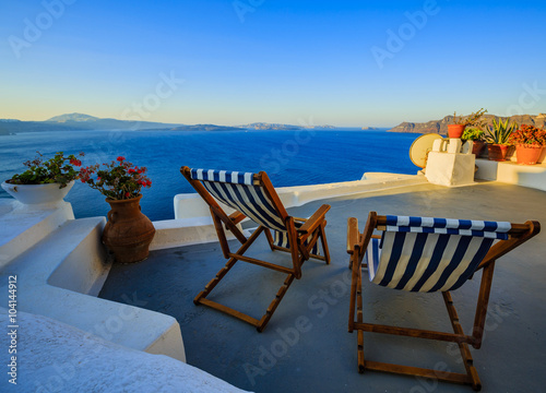 Beach chairs on the terrace at the beach, blue sea and sun in Greece