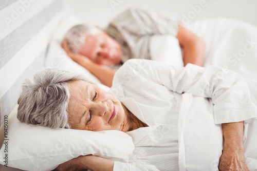 Senior couple sleeping on bed
