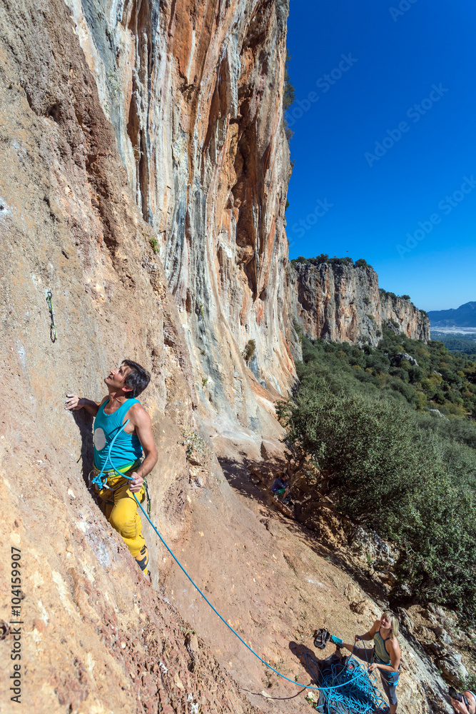 Fototapeta premium Mature male extreme Climber moving up on belay of partner