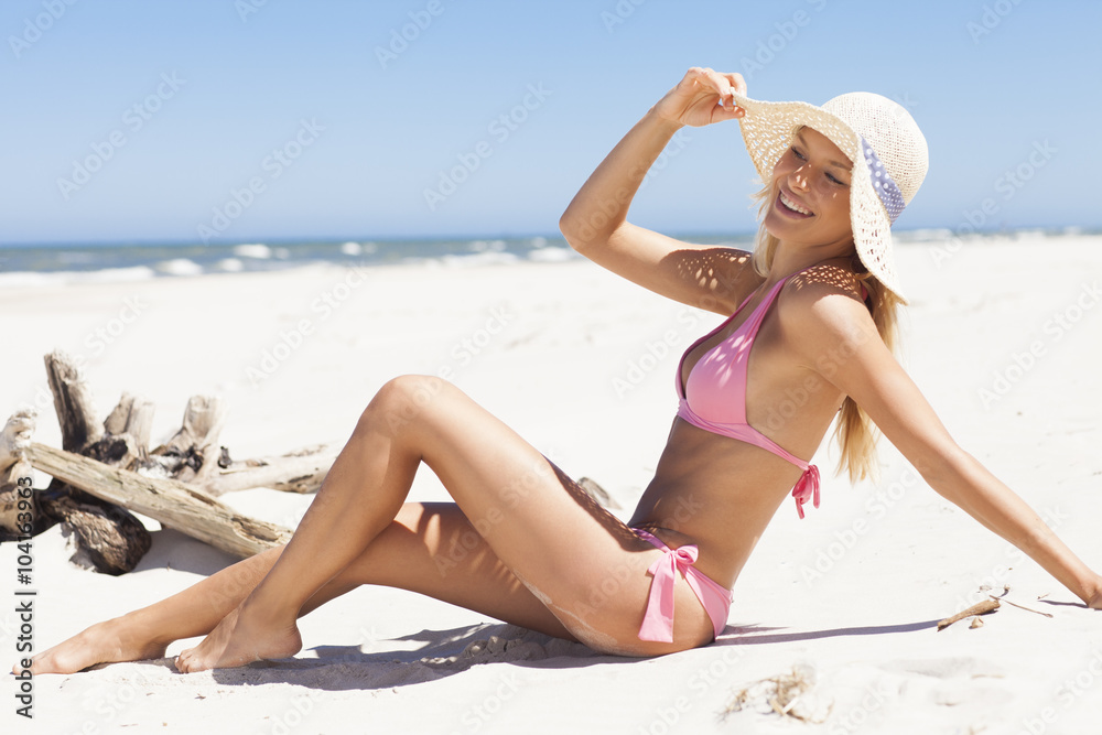 Young and attractive woman sunbathing on the beach in pink bikini Young and attractive woman sunbathing on the beach in pink bikini