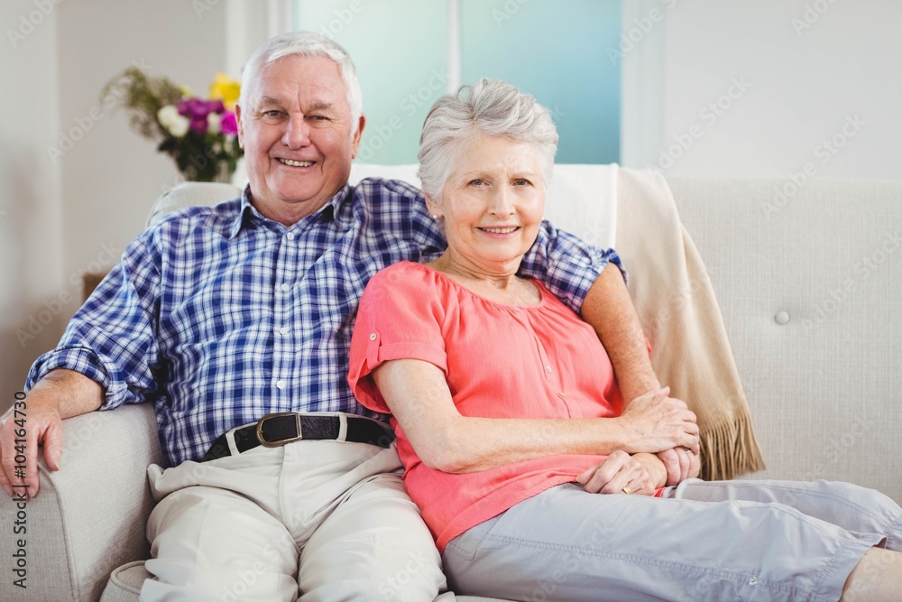 Senior couple sitting on sofa and smiling Senior couple sitting on sofa and smiling