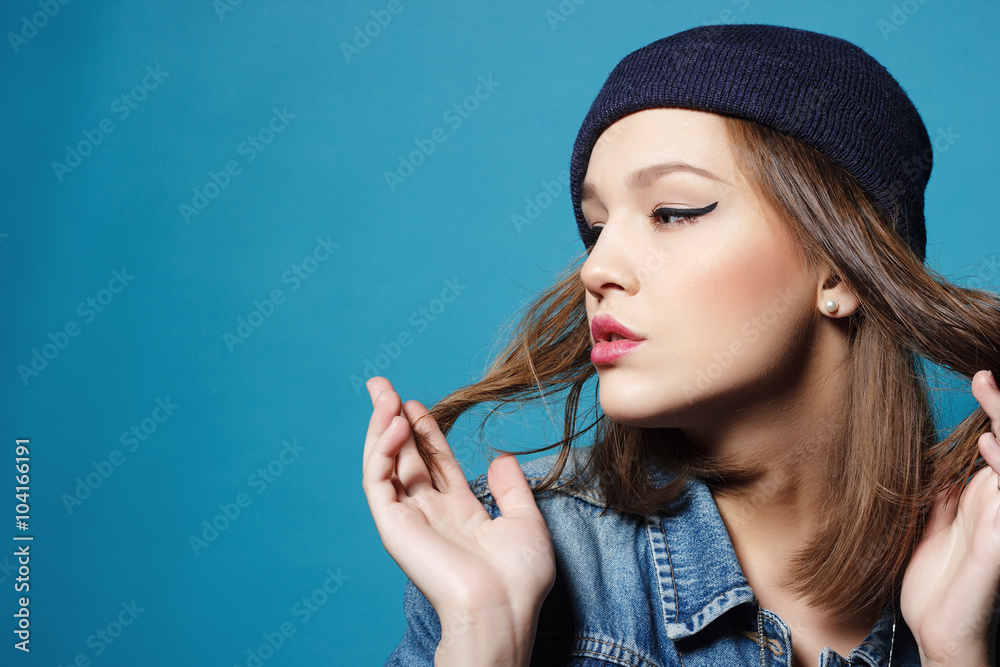 Obraz premium Closeup studio shot of pretty hipster teenage girl with beanie hat wearing jeans jacket looking at camera posing.
