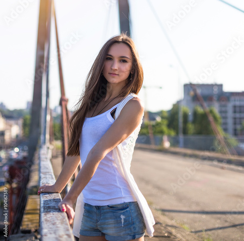 Young happy caucasian woman walkong on old bridge in city park outdoor. Relax lifestyle summer concept photo