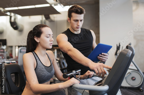 woman with trainer on exercise bike in gym