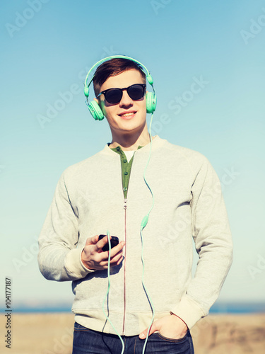 Принти на полотні happy young man in headphones with smartphone