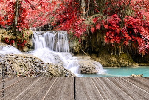 Vintage style wooden floor perspective with beautiful autumn waterfall.