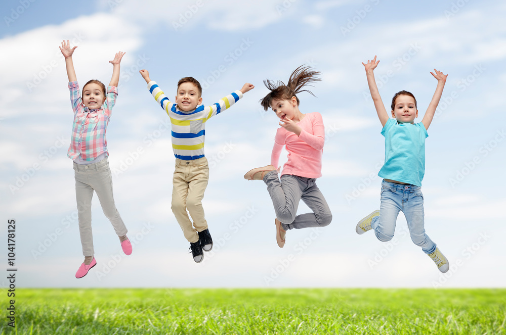 happy children jumping in air over sky and grass