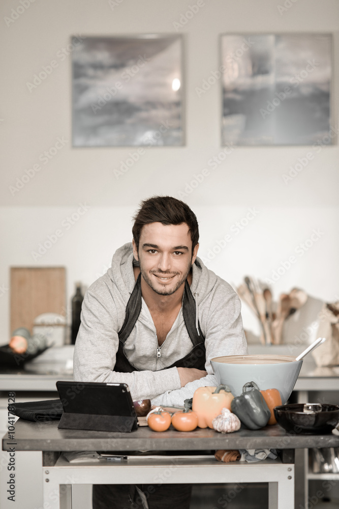 Portrait of a handsome young man cooking with digital tablet in Portrait of a handsome young man cooking with digital tablet in