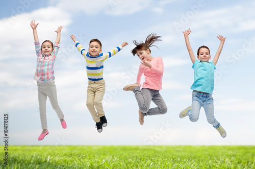 happy children jumping in air over sky and grass