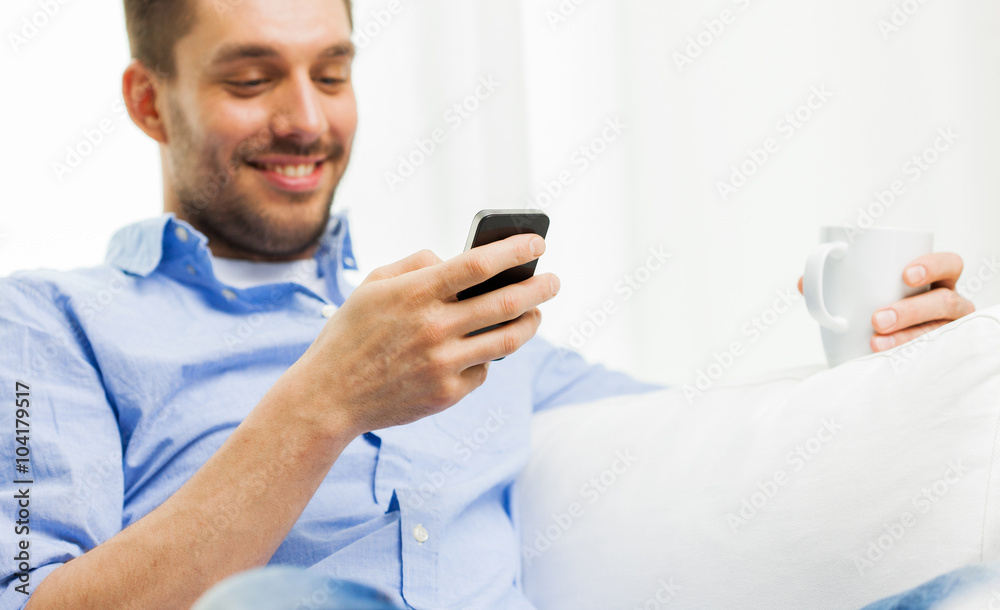 smiling man texting message on smartphone at home smiling man texting message on smartphone at home