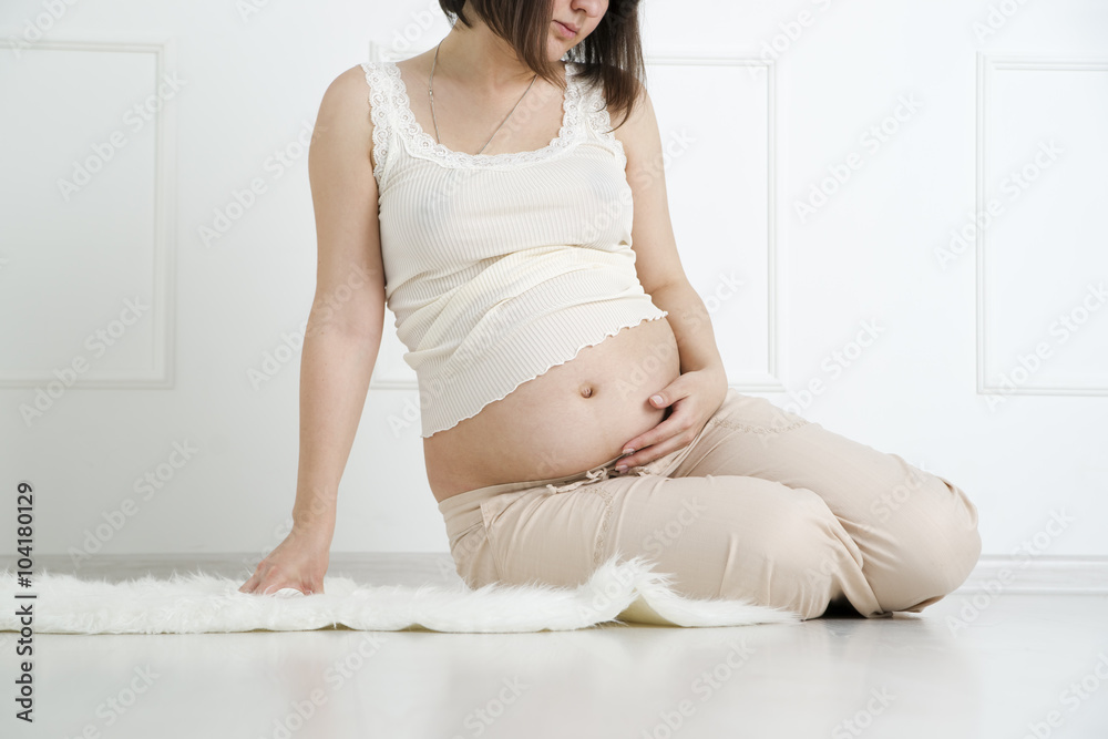 Beautiful young caucasian pregnant woman resting in the room Beautiful young caucasian pregnant woman resting in the room