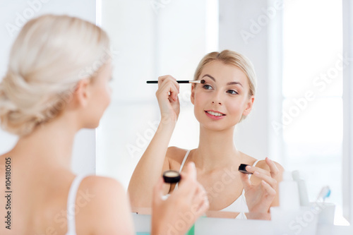 woman with makeup brush and eyeshade at bathroom