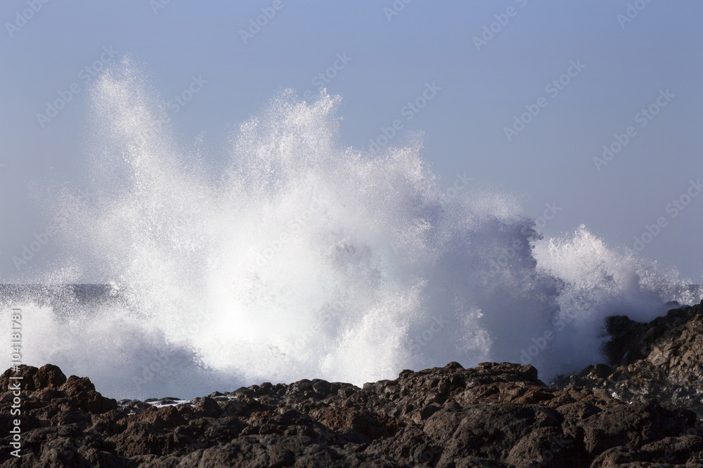 water splash or spray by breaking waves on rocky shore of punta
