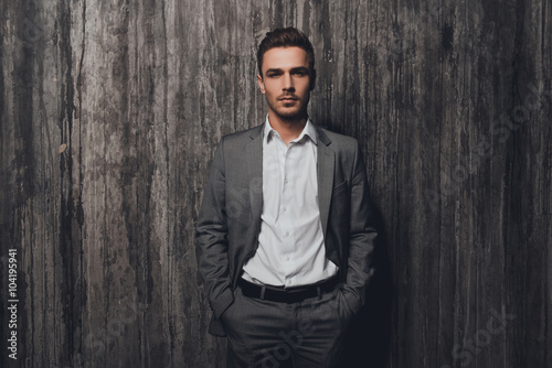 Handsome businessman in gray suit holding hands in pockets