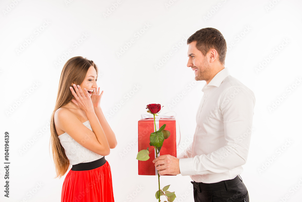 Smiling boy giving to his girlfriend a gift and a rose, girl sur Smiling boy giving to his girlfriend a gift and a rose, girl sur