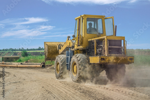 yellow bulldozer rides on the sand road