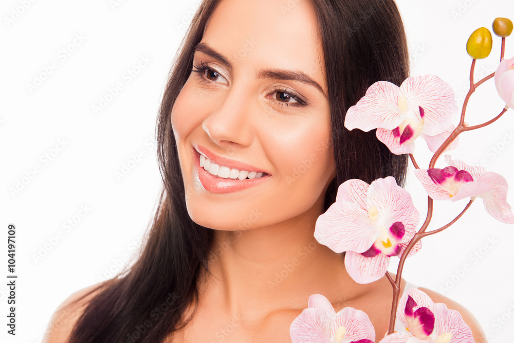 Close up photo of smiling brunette holding orchid near her face Close up photo of smiling brunette holding orchid near her face