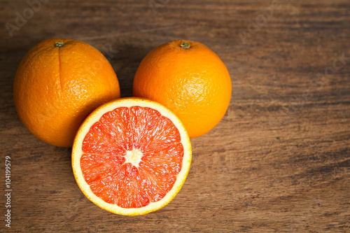 Fresh oranges with slices on wooden background.