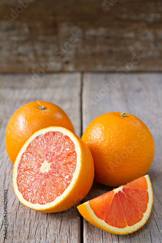 Fresh oranges with slices on wooden background.