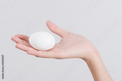 Woman hand holding White egg, isolated on white background
