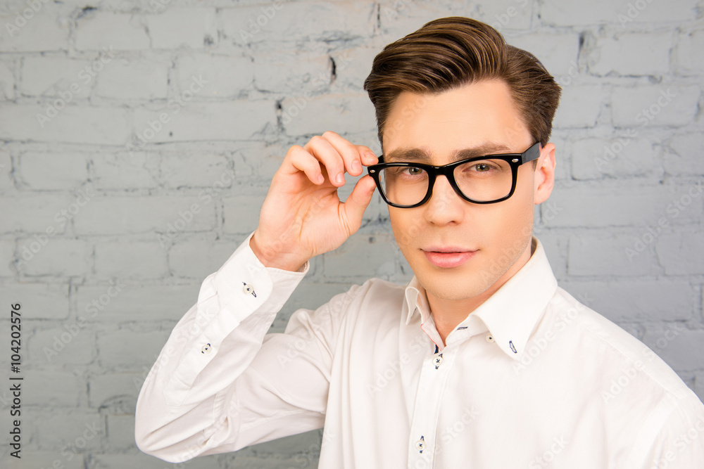 Attractive young man in white shirt touching his glasses Attractive young man in white shirt touching his glasses