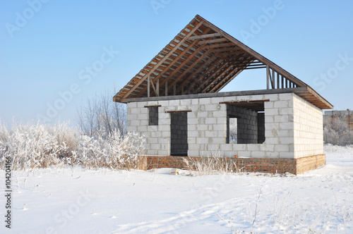 Building a Home During Winter. Building new house from autoclaved aerated concrete blocks vs bricks with unfinished roofing metal tiles construction. © bildlove