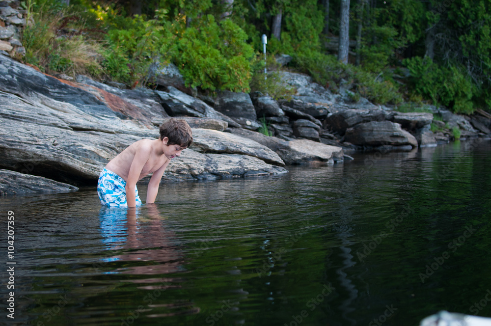 Fototapeta premium boy child standing in a lake looking into the water