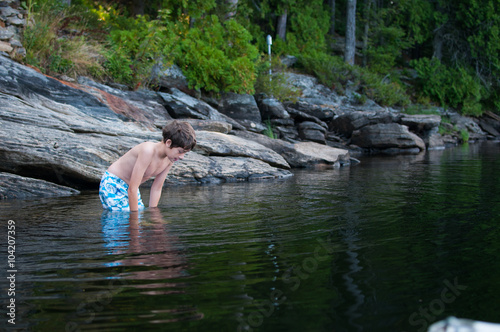 boy child standing in a lake looking into the water