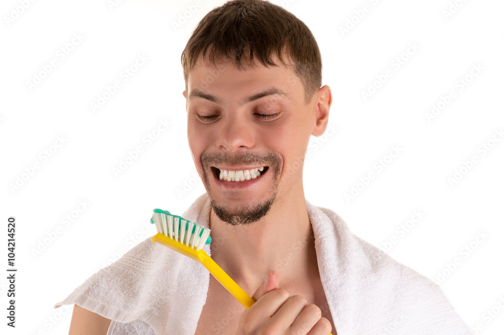 portrait of a man smiling broadly looking at a giant white toothbrush with toothpaste in his hand portrait of a man smiling broadly looking at a giant white toothbrush with toothpaste in his hand