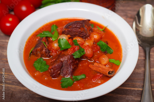 National Greek dish stifado with beef, tomatoes and onions, stewed in red wine with Herbs on a wooden background, horizontal