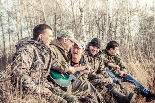 group of cheerful men sitting together in a row during outdoor recreation in park 
