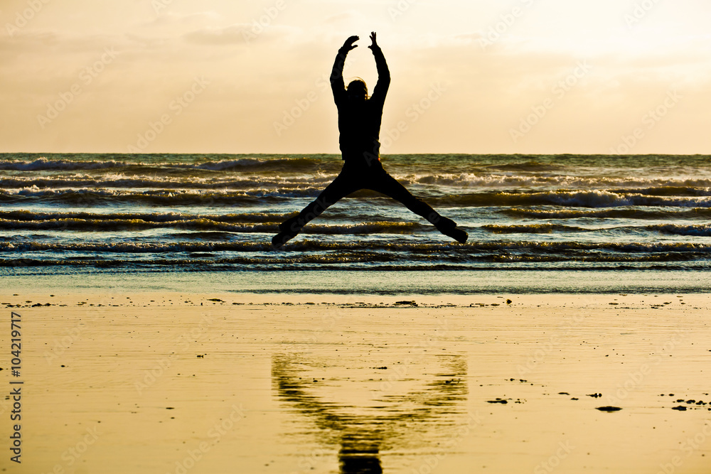 woman jumping having fun on the beach in an ambiguous silhouette