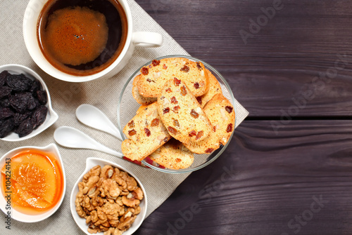 Homemade biscotti are laid out in the form of words next to a large cup of hot black coffee on vintage rustic table