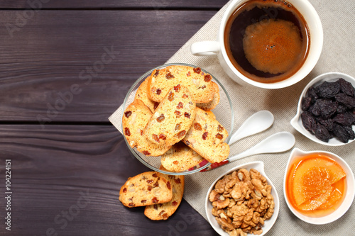 Homemade biscotti are laid out in the form of words next to a large cup of hot black coffee on vintage rustic table