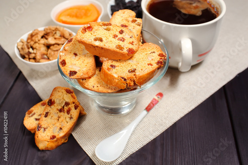 Homemade biscotti are laid out in the form of words next to a large cup of hot black coffee on vintage rustic table