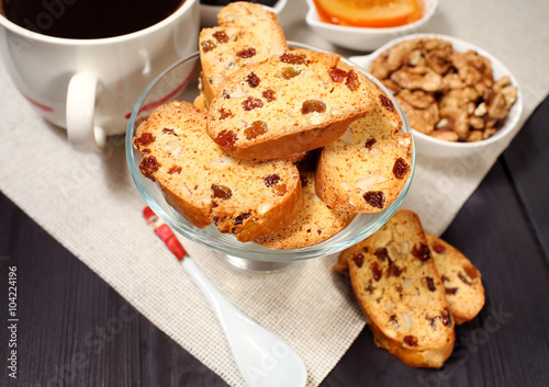 Homemade biscotti are laid out in the form of words next to a large cup of hot black coffee on vintage rustic table