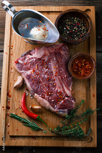 Raw fresh meat T-Bone Steak with herbs and spices and chilli pep