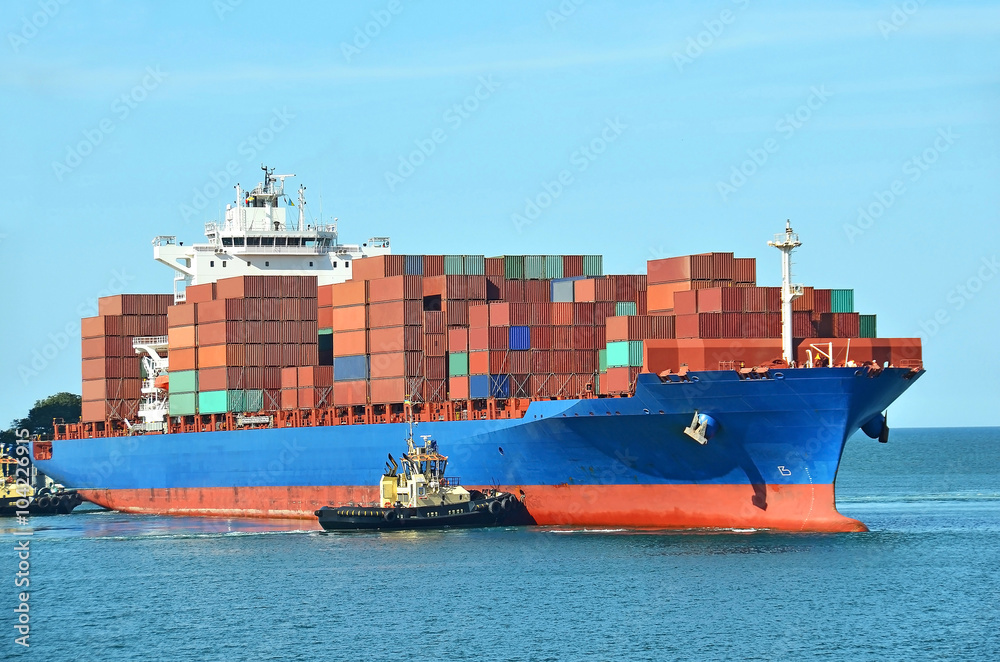 Fototapeta premium Tugboat assisting container cargo ship