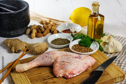 Raw chicken leg with ingredients to prepare grilled meat skewers