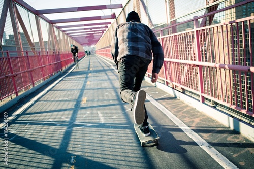 Long shadow of a skateboarder cruising through crosswalk. Photographed in Feb 2016.