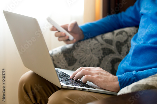 Young man using laptop and phone