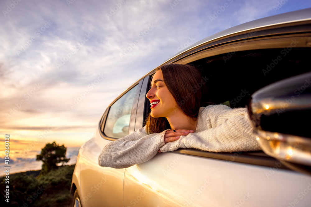 Φωτογραφία Young woman looking out the car window on the roadside above the clouds on the sunrise